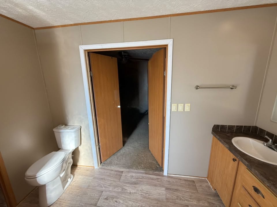 Remodeled bathroom with a wood vanity, toilet, and new plank flooring