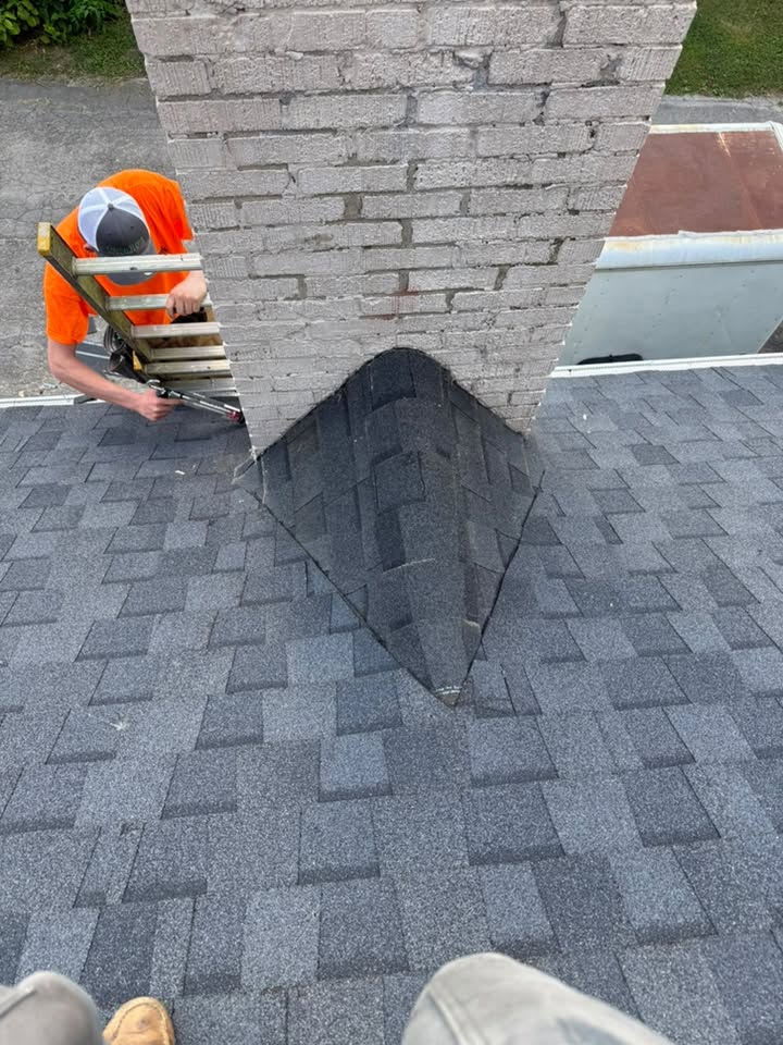 McAllister Construction crew member installing shingles around a brick chimney